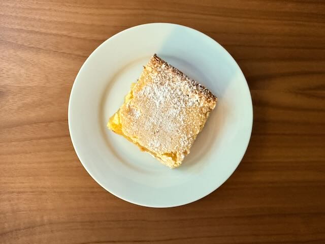 Custard cream slice with powdered sugar topping on a white ceramic plate